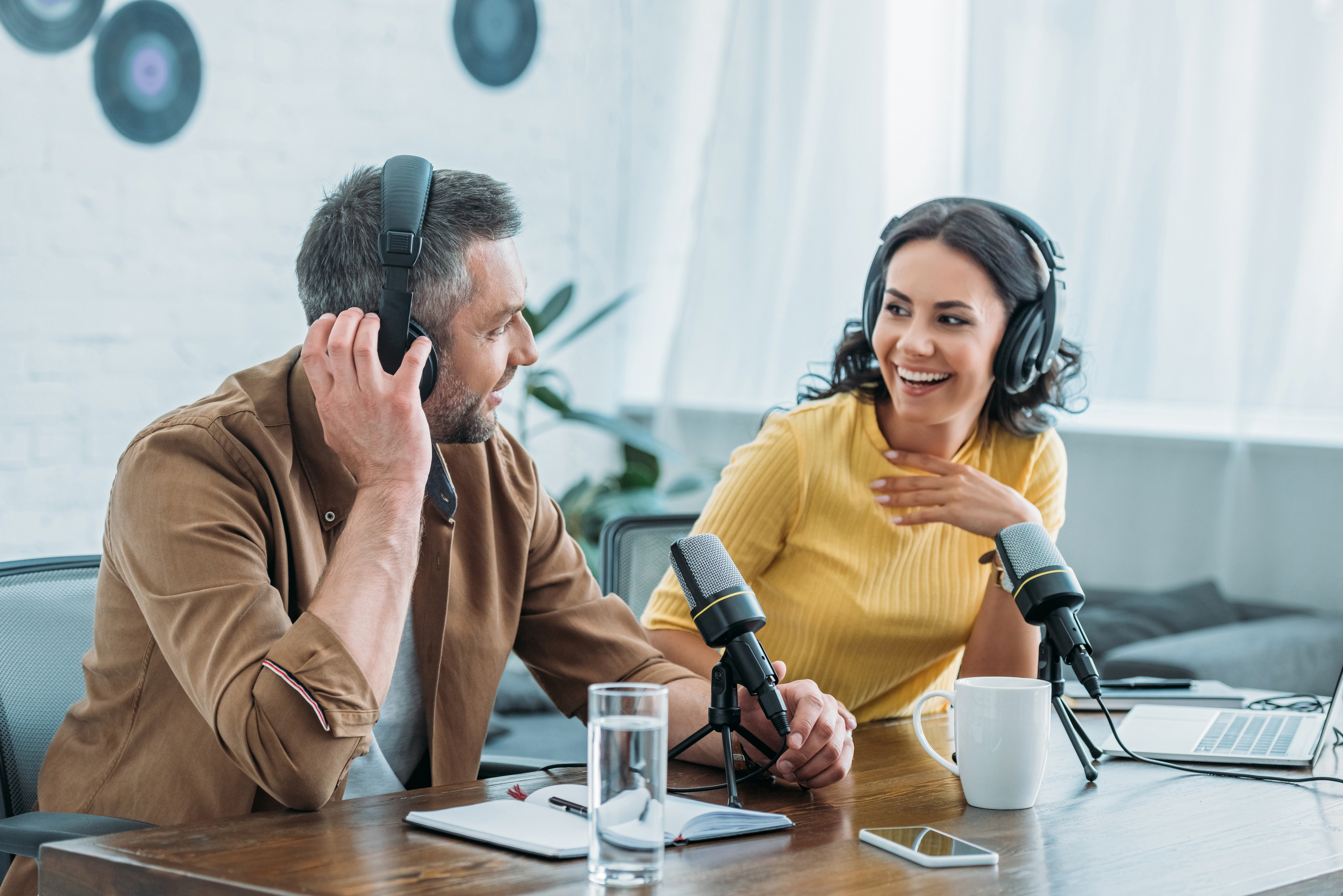 two cheerful radio hosts in headphones recording podcast in broadcasting studio
