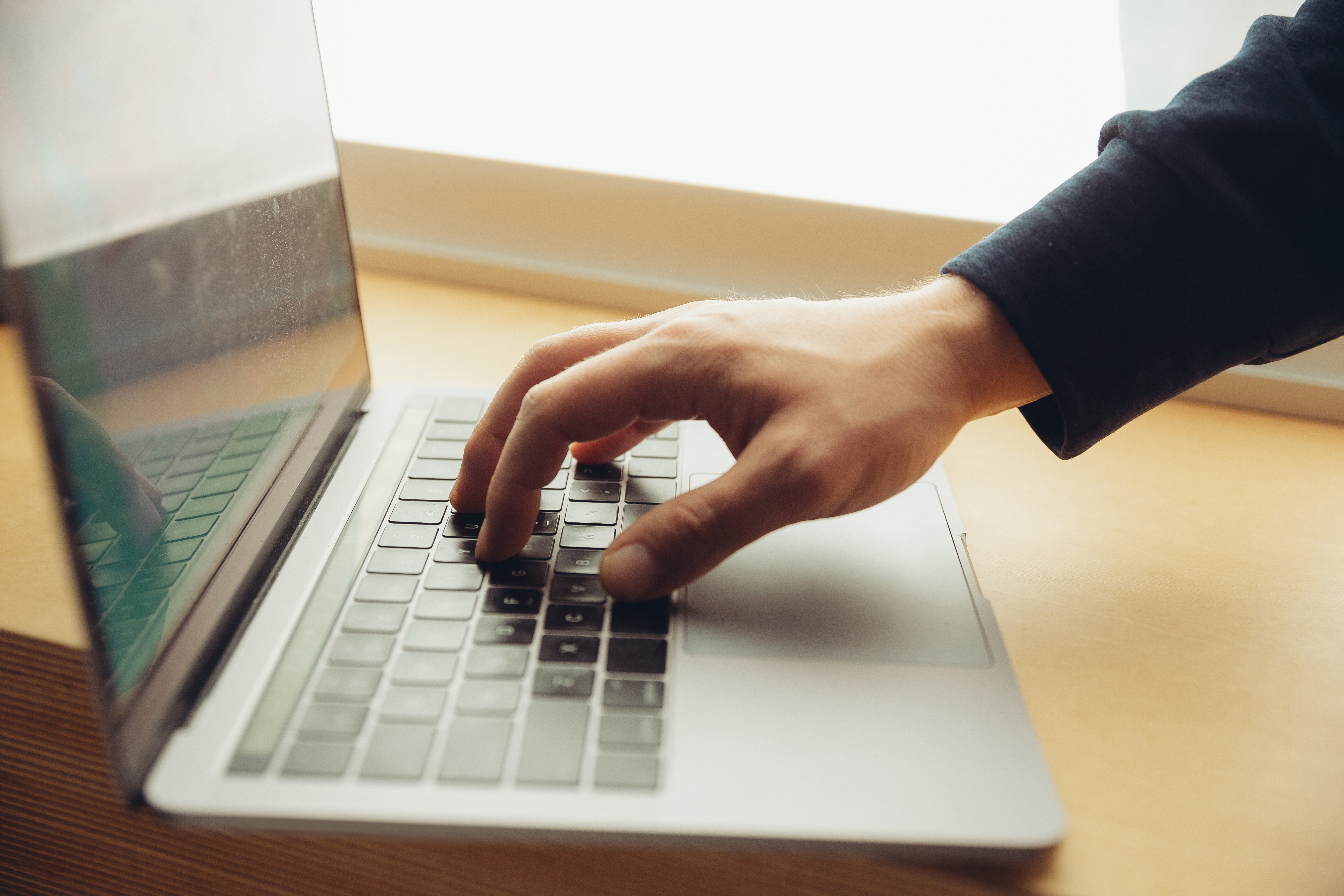 Close-up of male fingers typing a business document, note or search key on the laptop